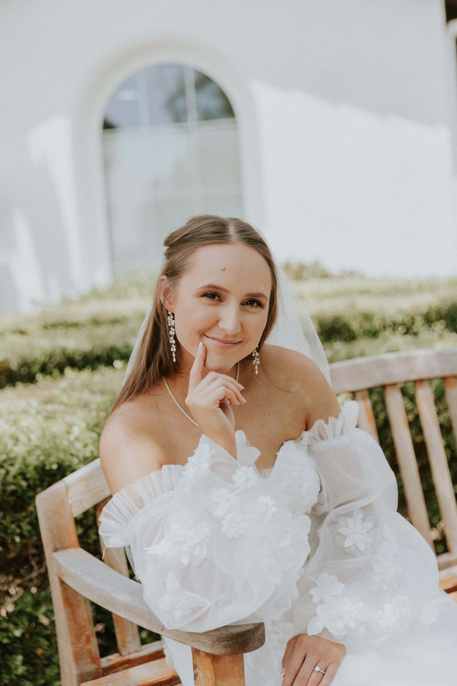 Irelyn smiling on a garden bench in her off-shoulder dress