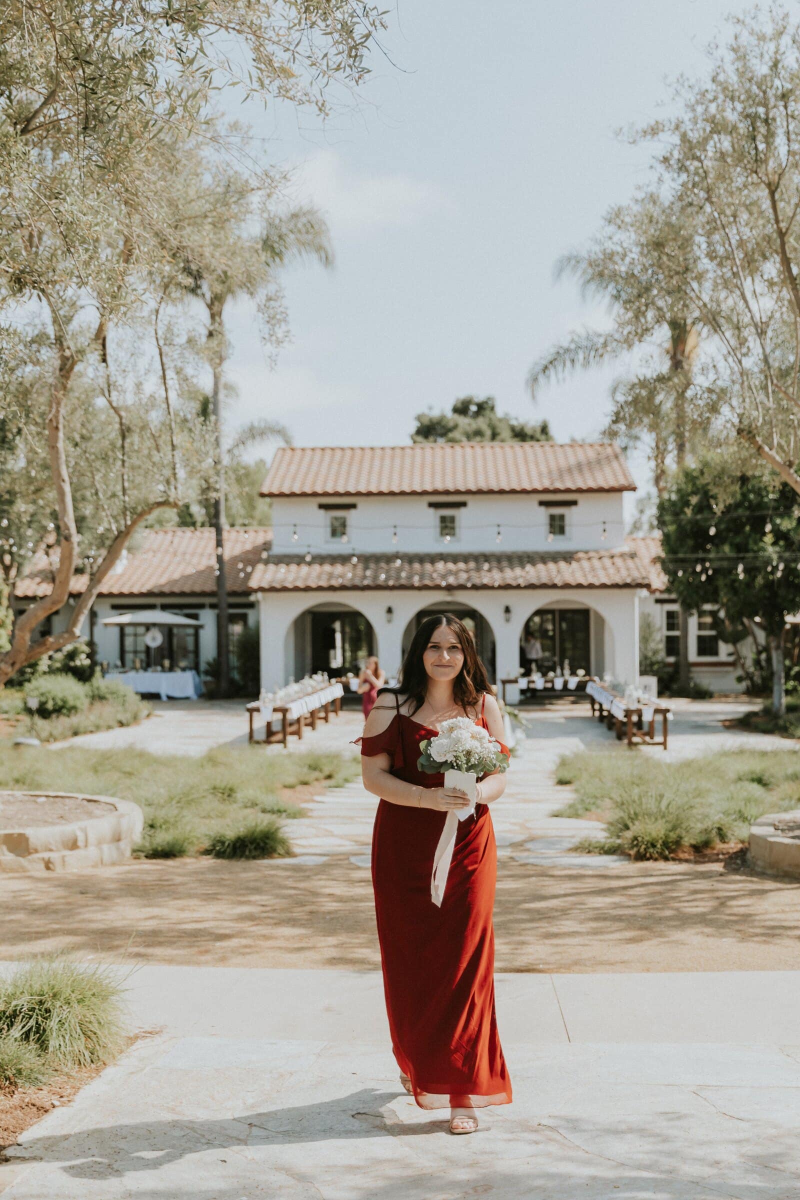A bridesmaid in red walking down the garden path