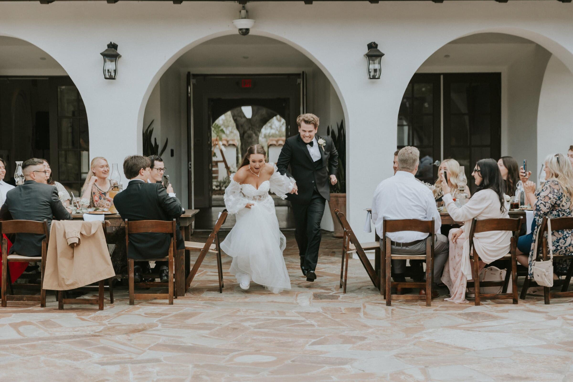 Aleck and Irelyn walking into the reception past the long tables