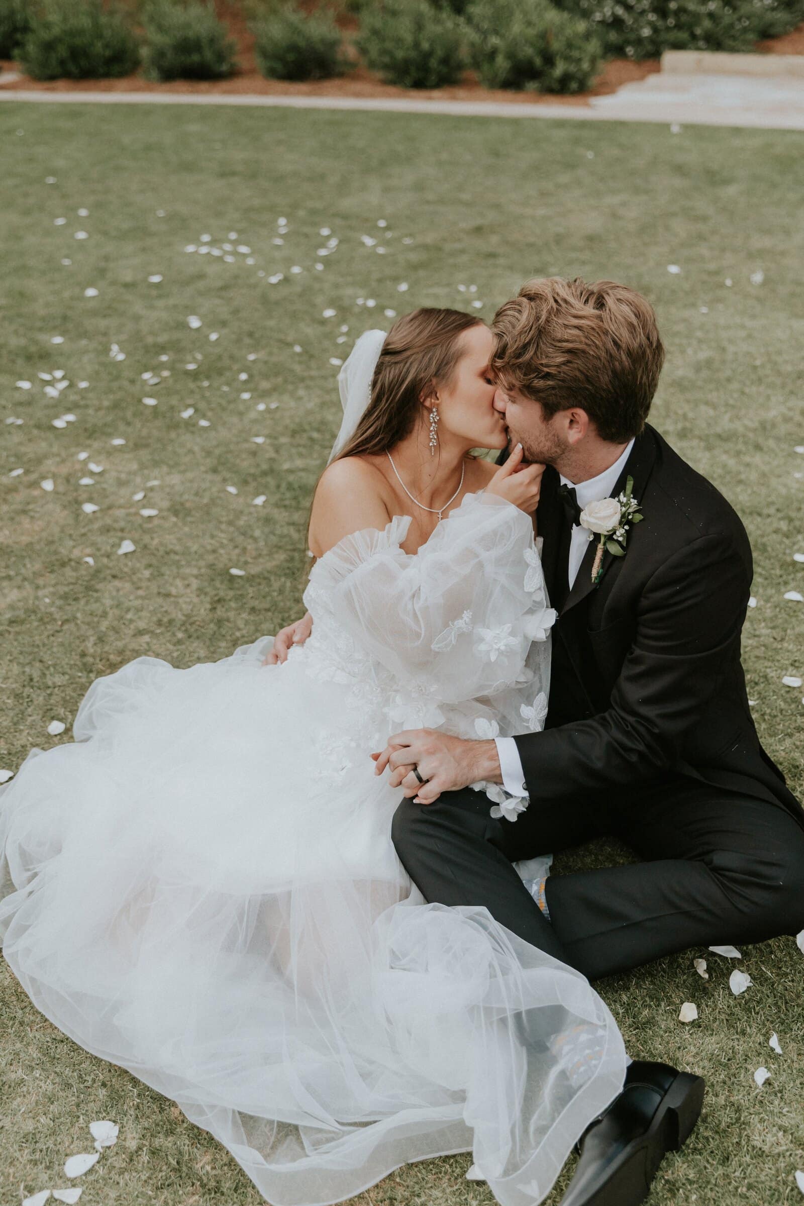 Aleck and Irelyn kissing on the lawn, her gown spread around them