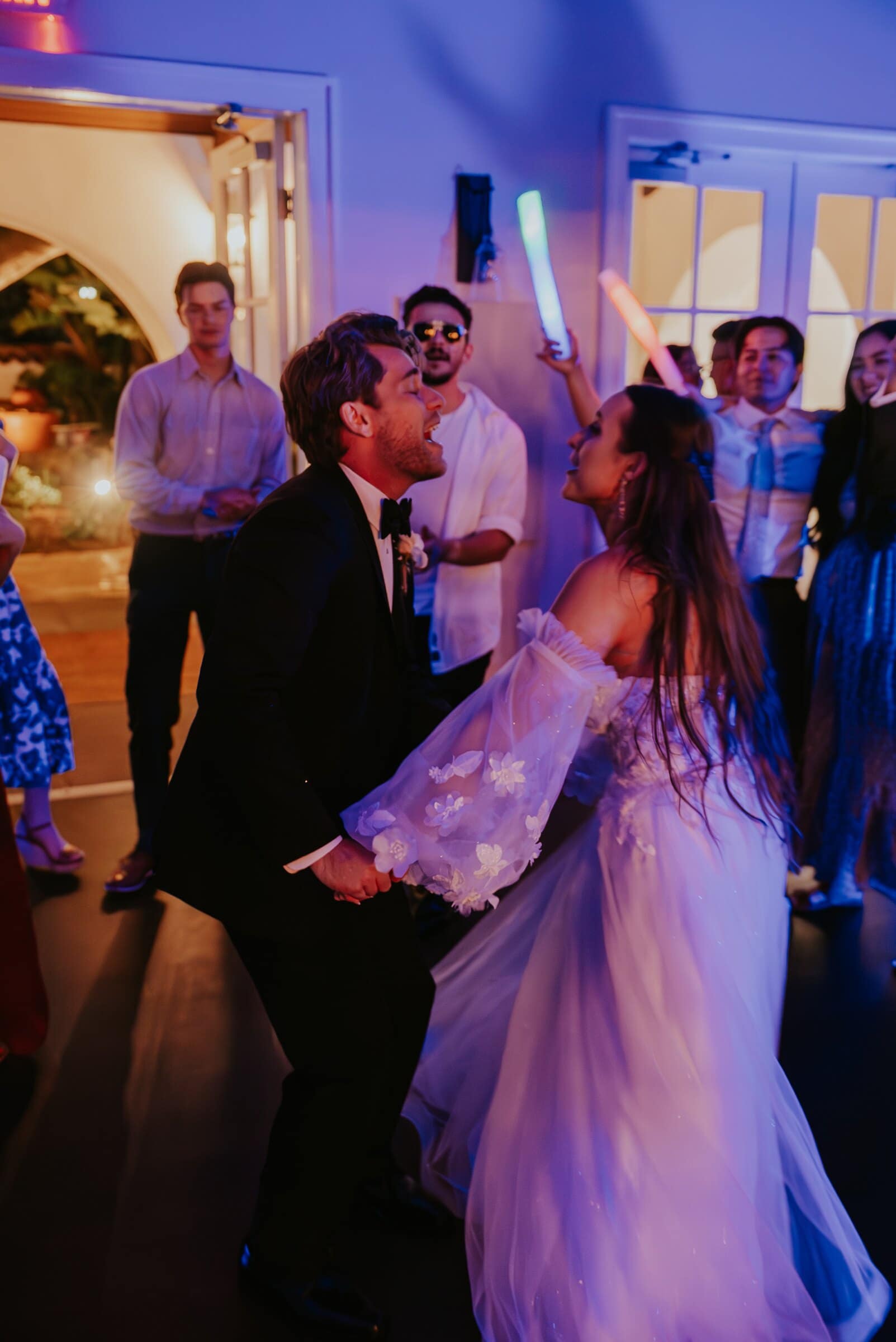 Aleck and Irelyn dancing in purple light as friends wave glow sticks