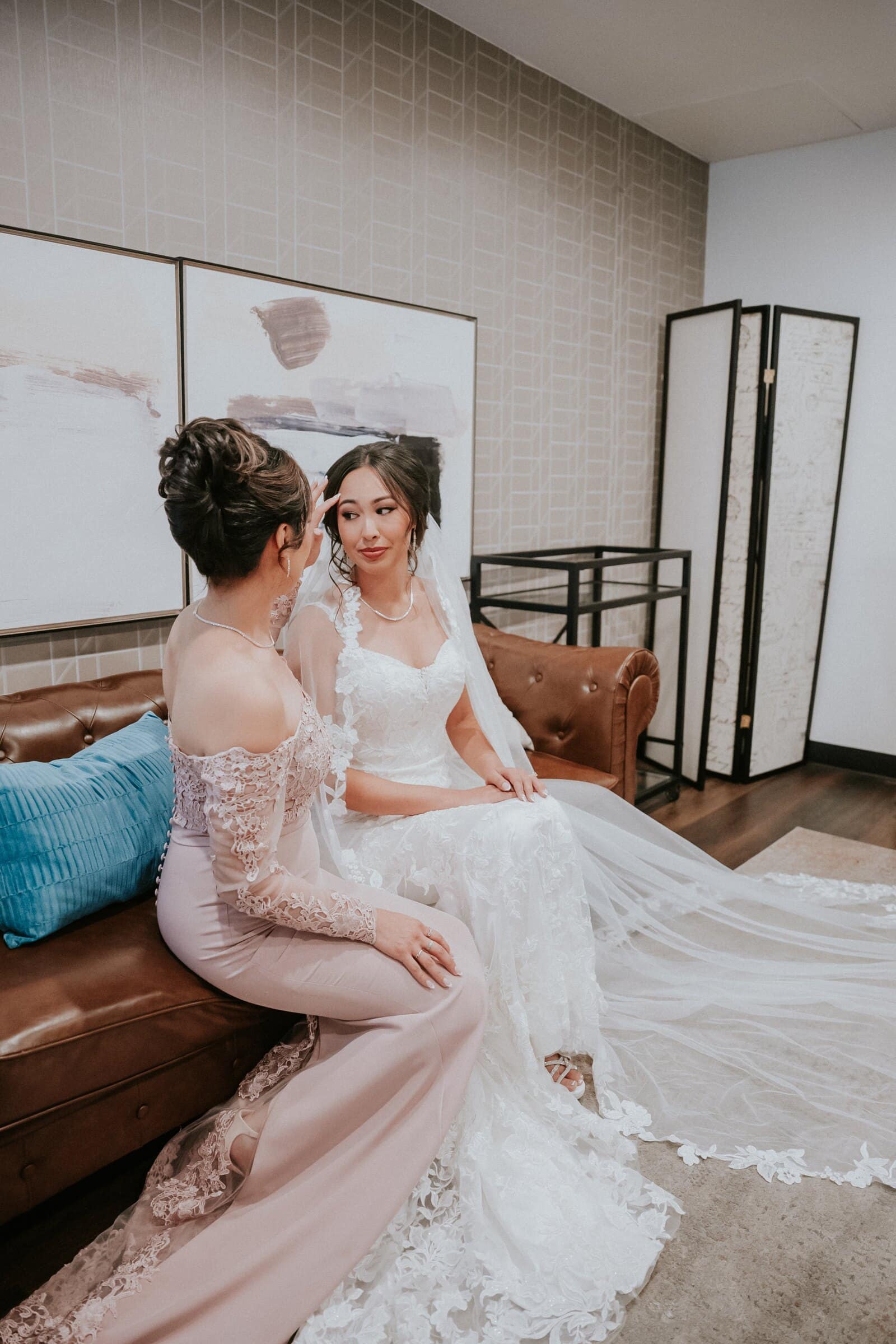 Ariana sitting with a bridesmaid in blush on a leather sofa