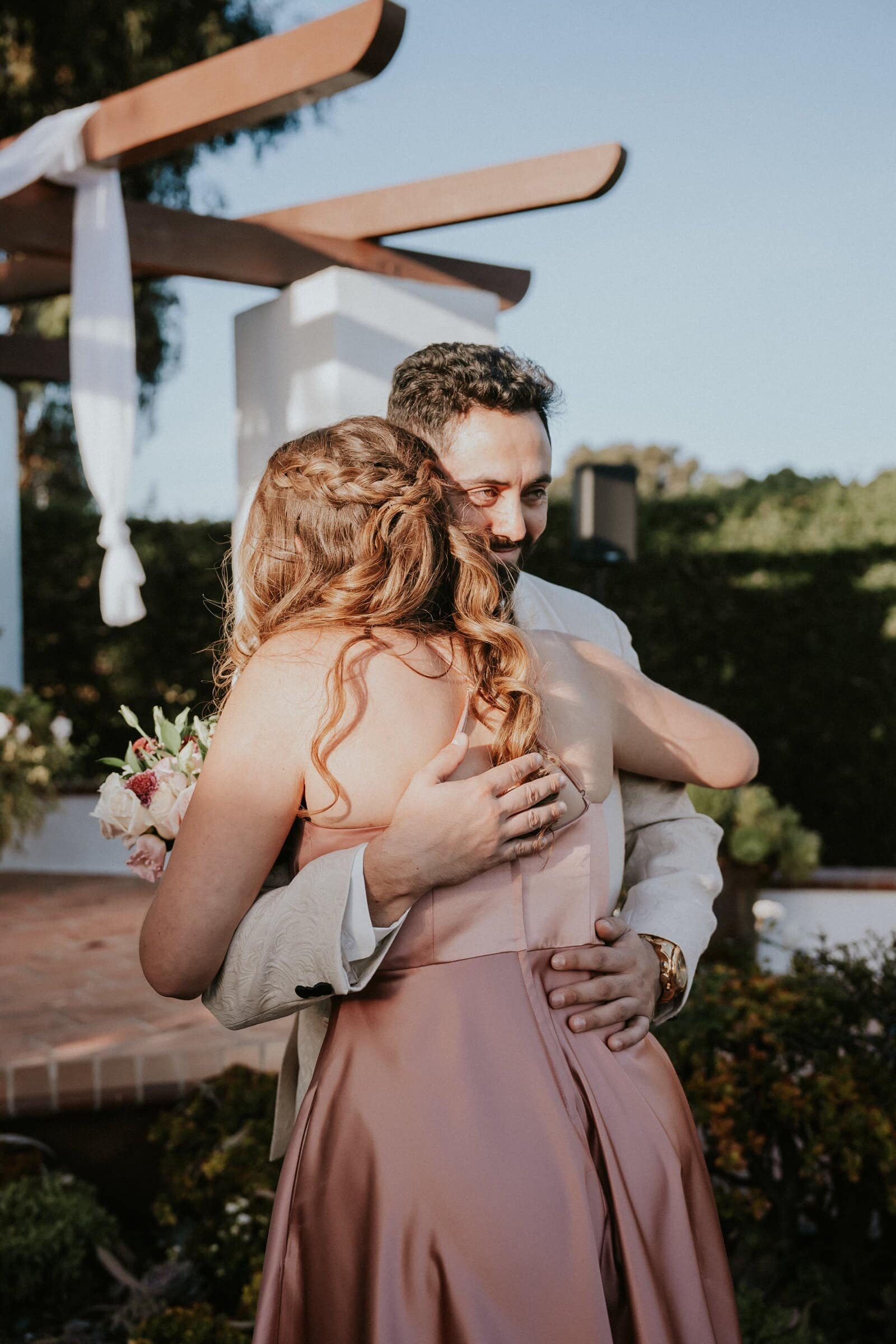 Dom hugging a bridesmaid in blush pink