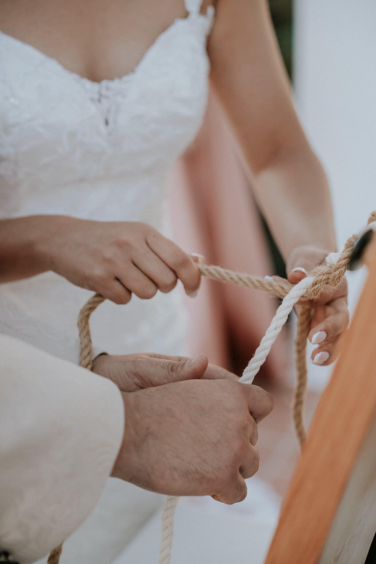Ariana and Dom's hands tying a cord during the ceremony