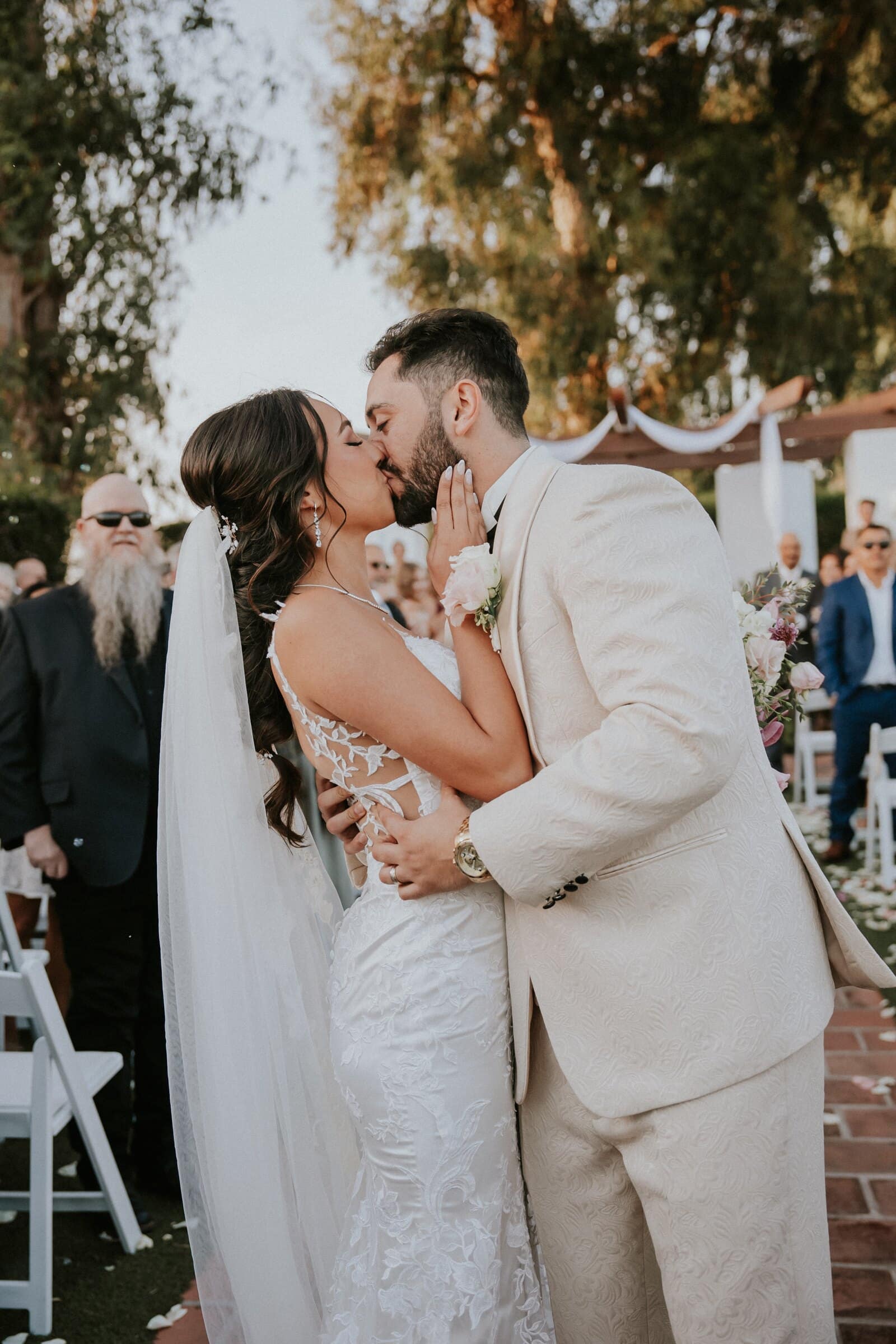 Ariana and Dom kissing in the aisle as guests stand