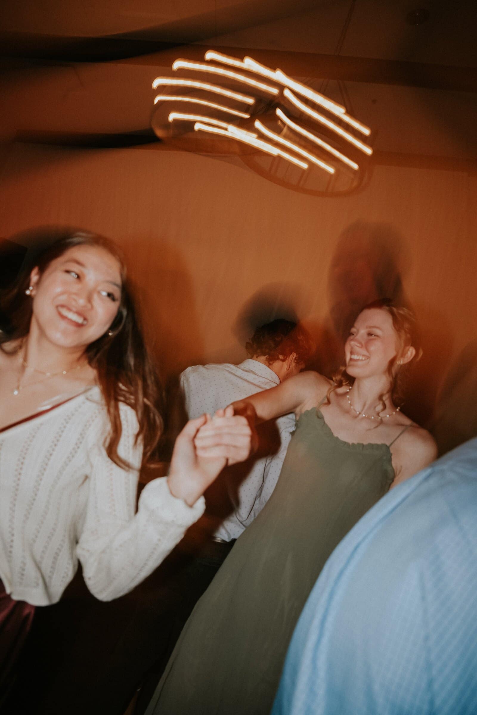 Friends dancing as the chandeliers streak into lines of light