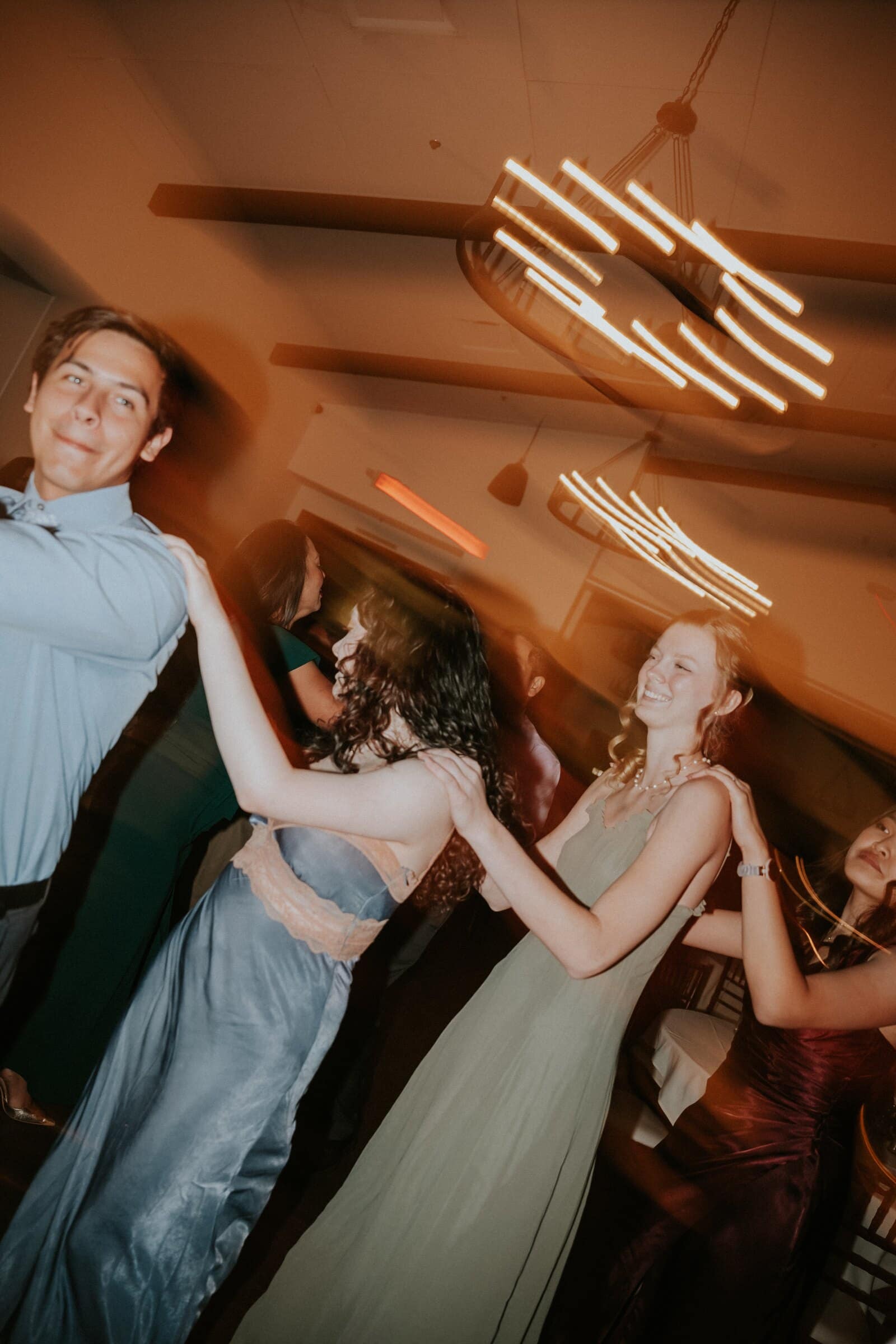 Bridesmaids twirling under streaking chandelier lights