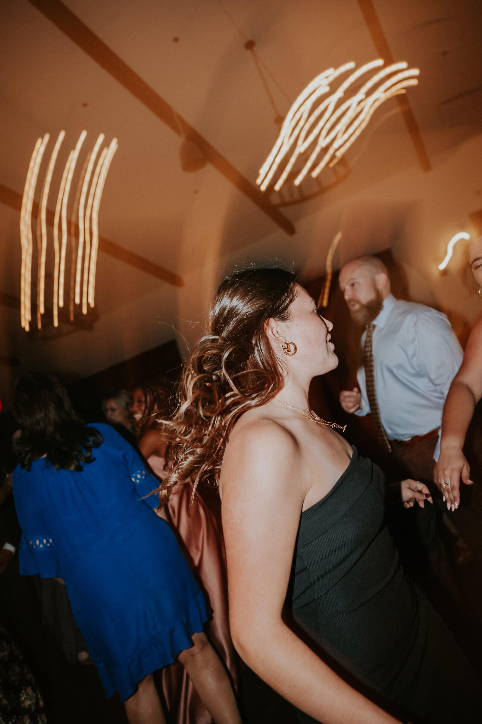A guest in a black dress dancing beneath streaks of light