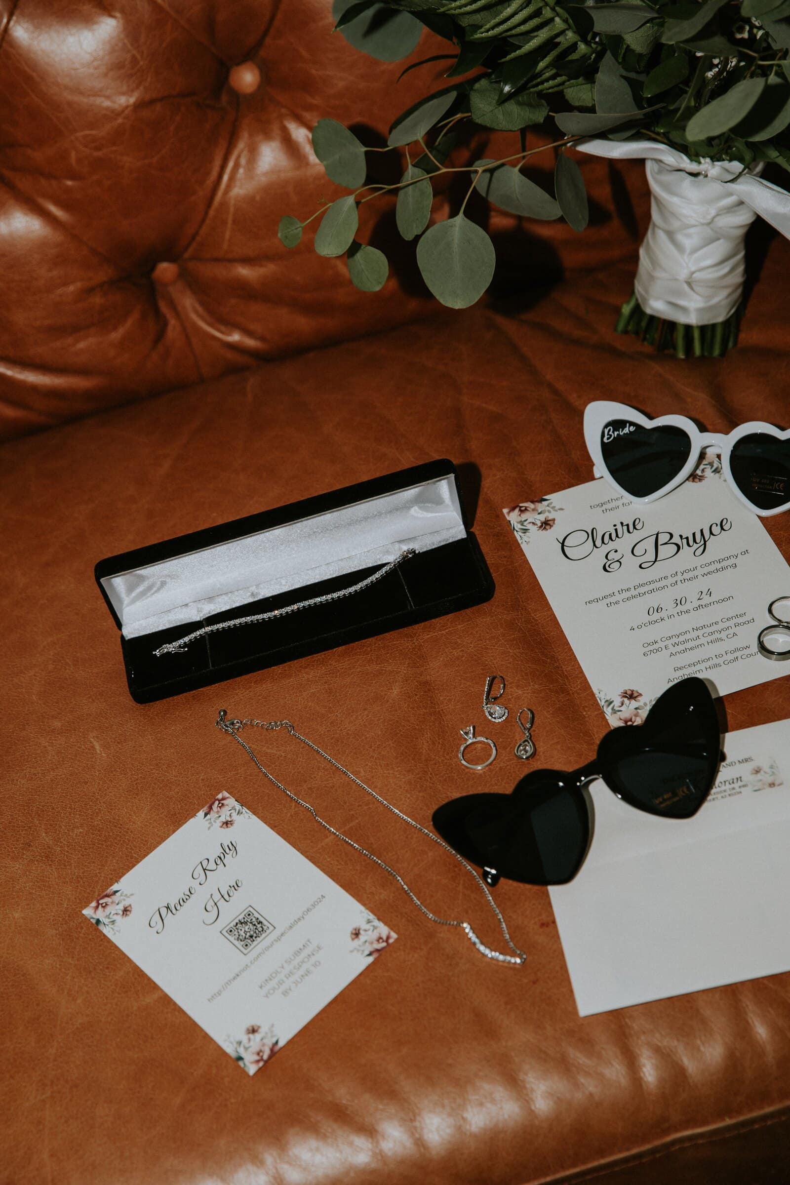 Heart-shaped sunglasses, a bracelet box and the invitation on a leather sofa