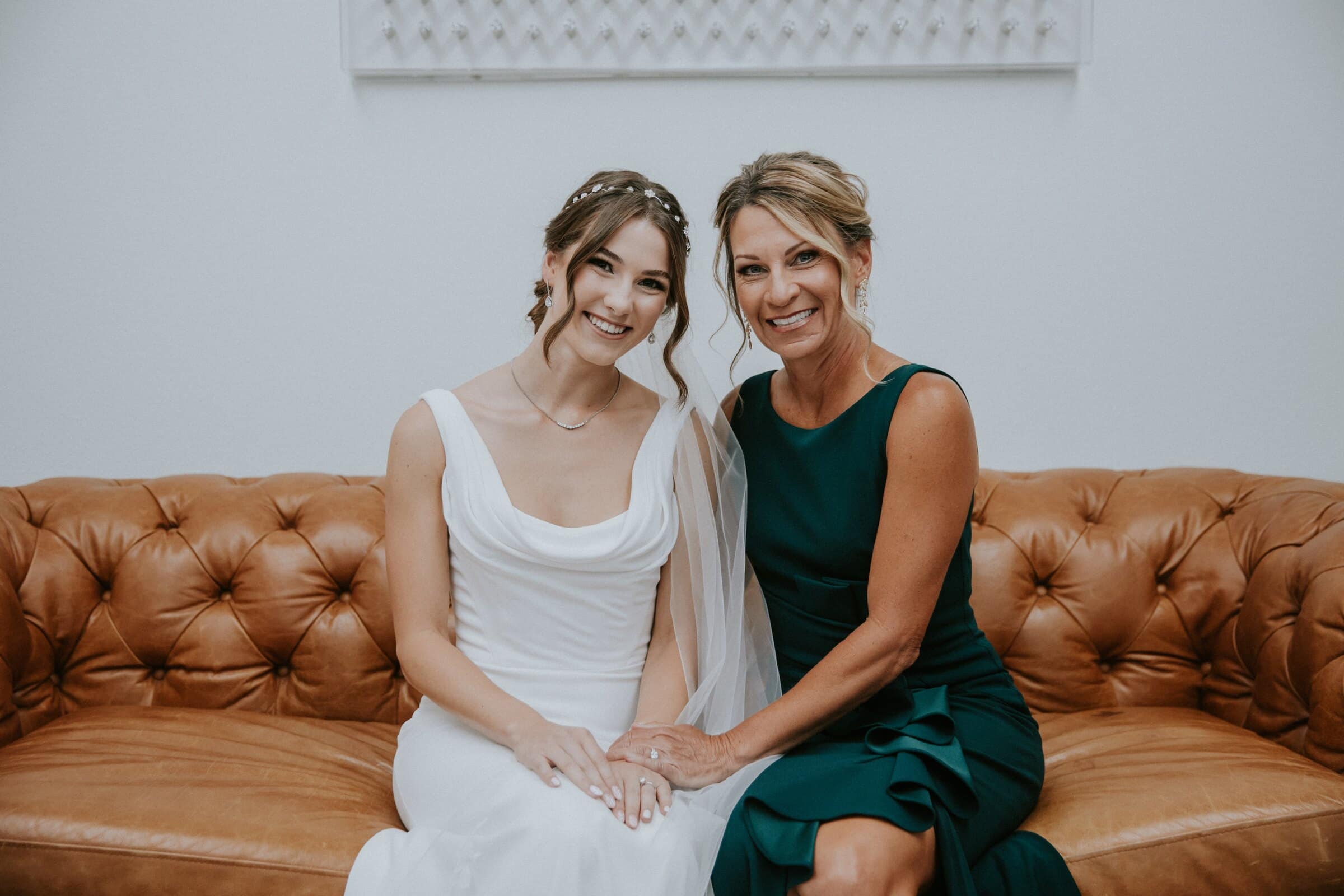 Claire laughing on a leather sofa beside a woman in a green dress
