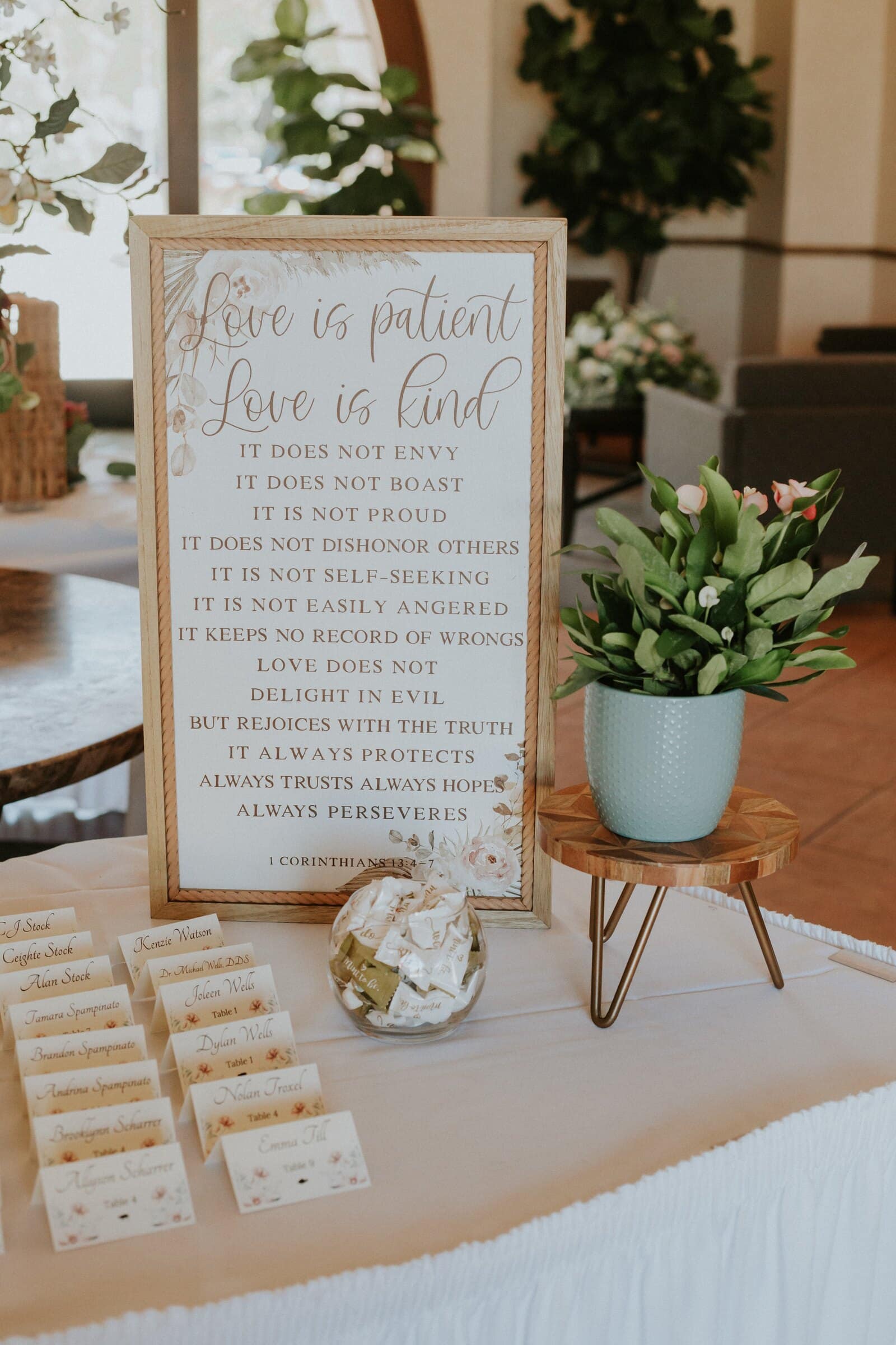 A "Love is patient" sign beside the escort cards
