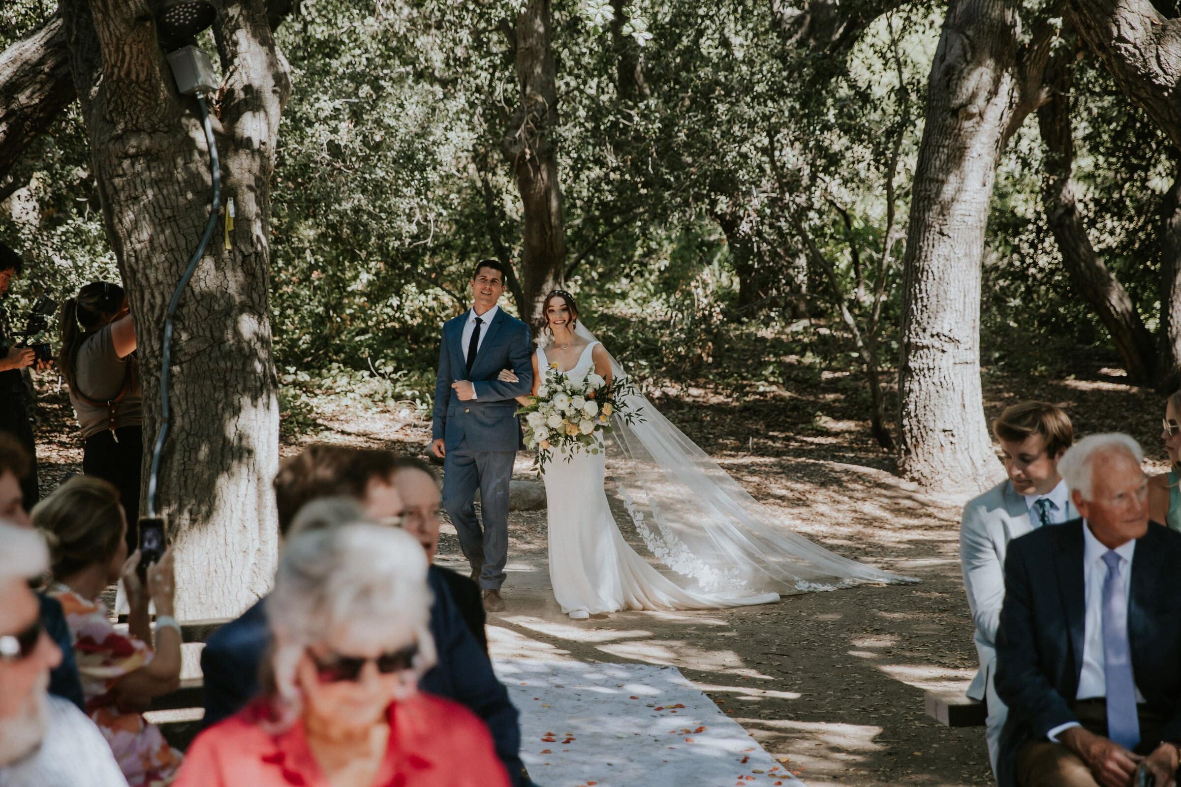 Claire walking down the aisle under the oak trees