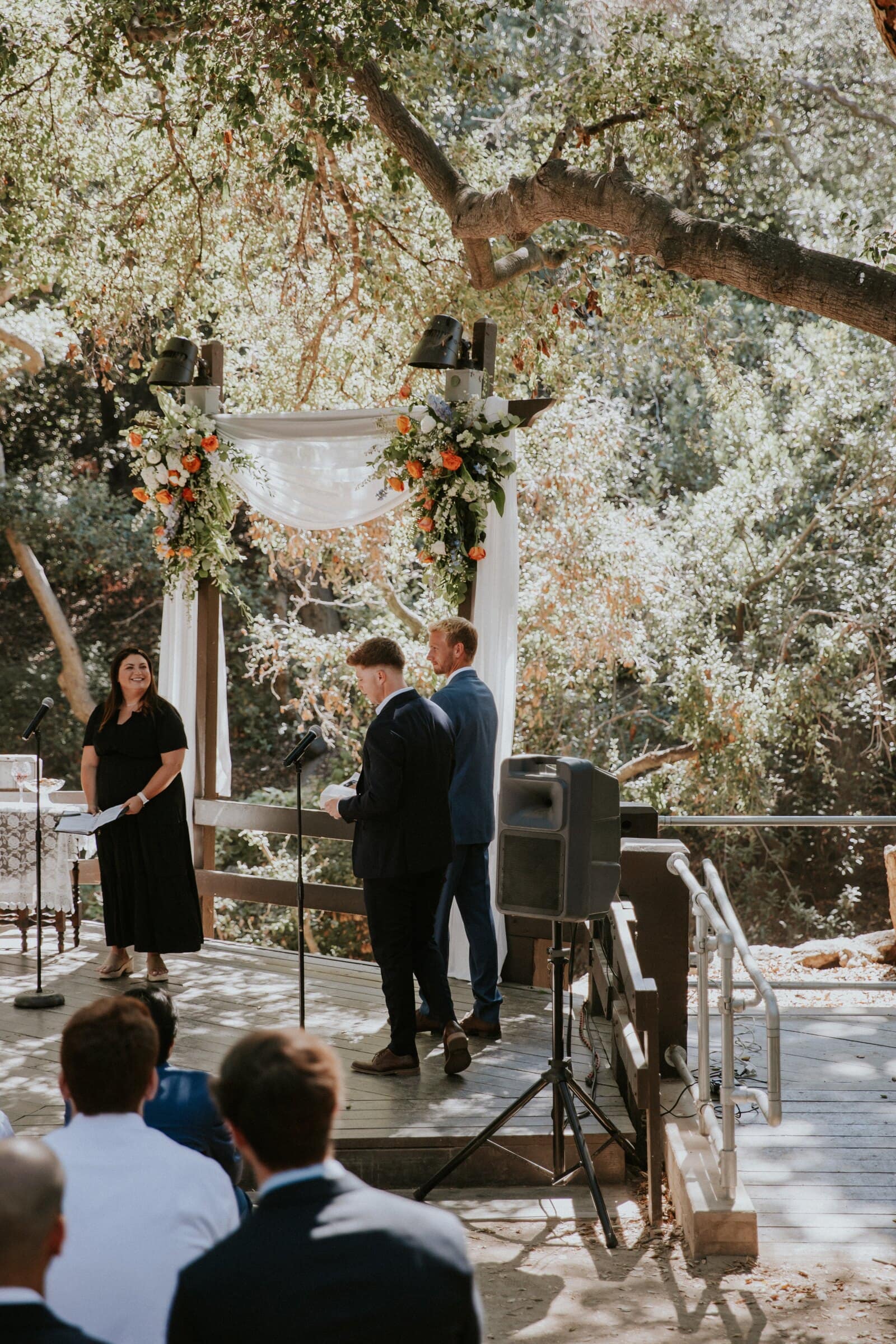 The ceremony on a wooden deck beneath the oaks