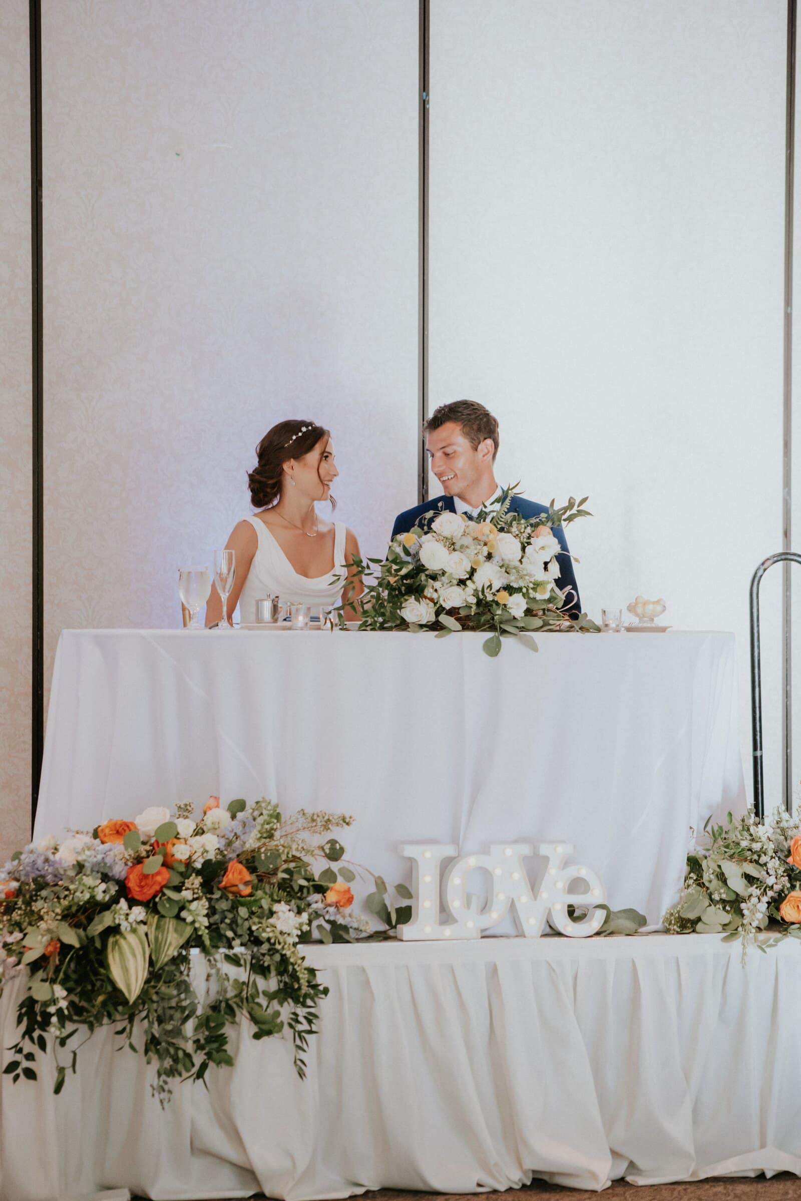Claire and Bryce at the sweetheart table behind a LOVE sign