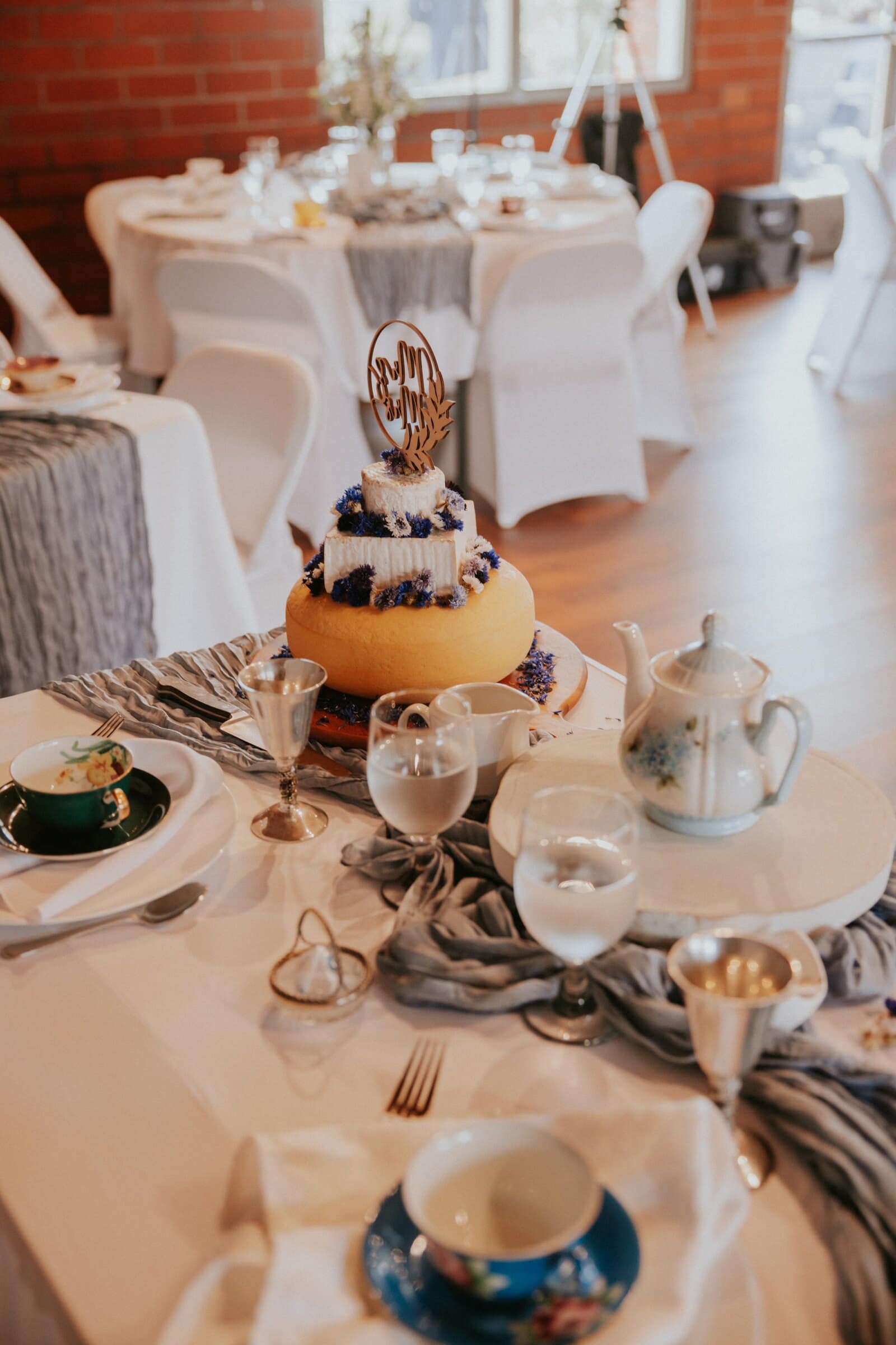 A reception table set with teacups, blue ribbon and the cake
