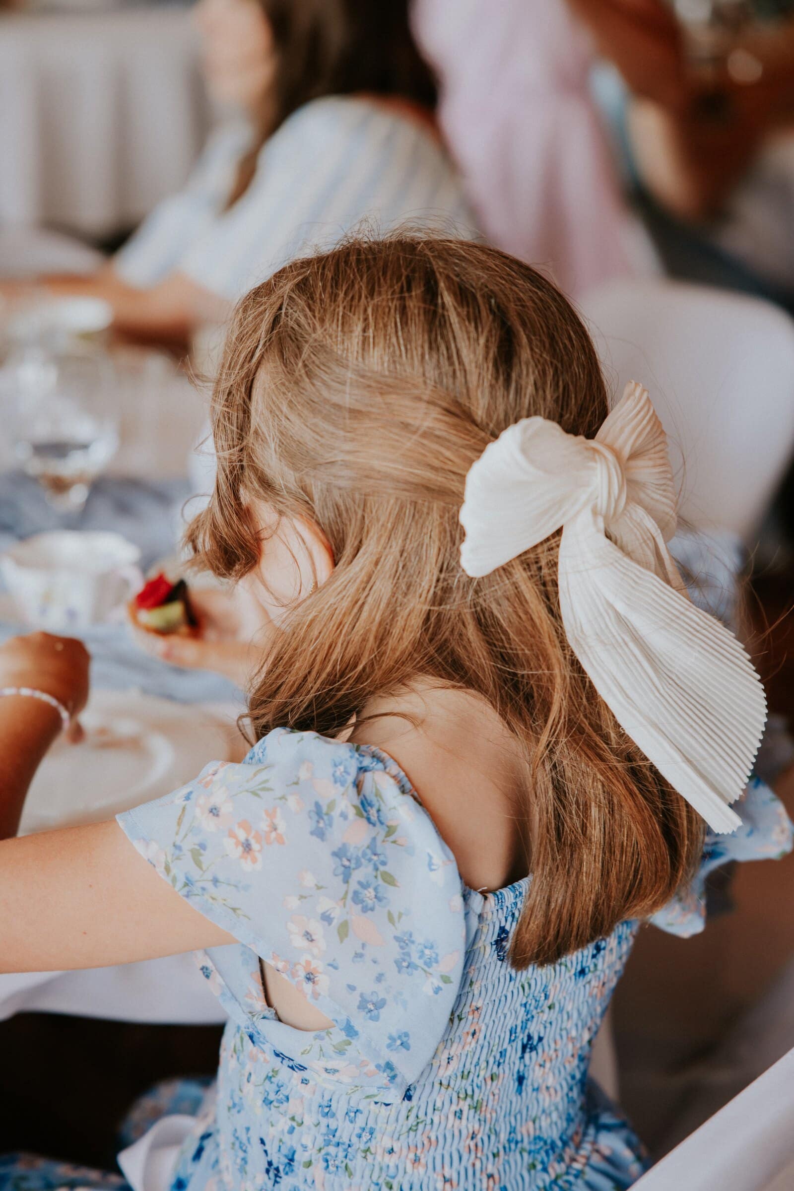 A little girl with a white bow in her hair at the reception table