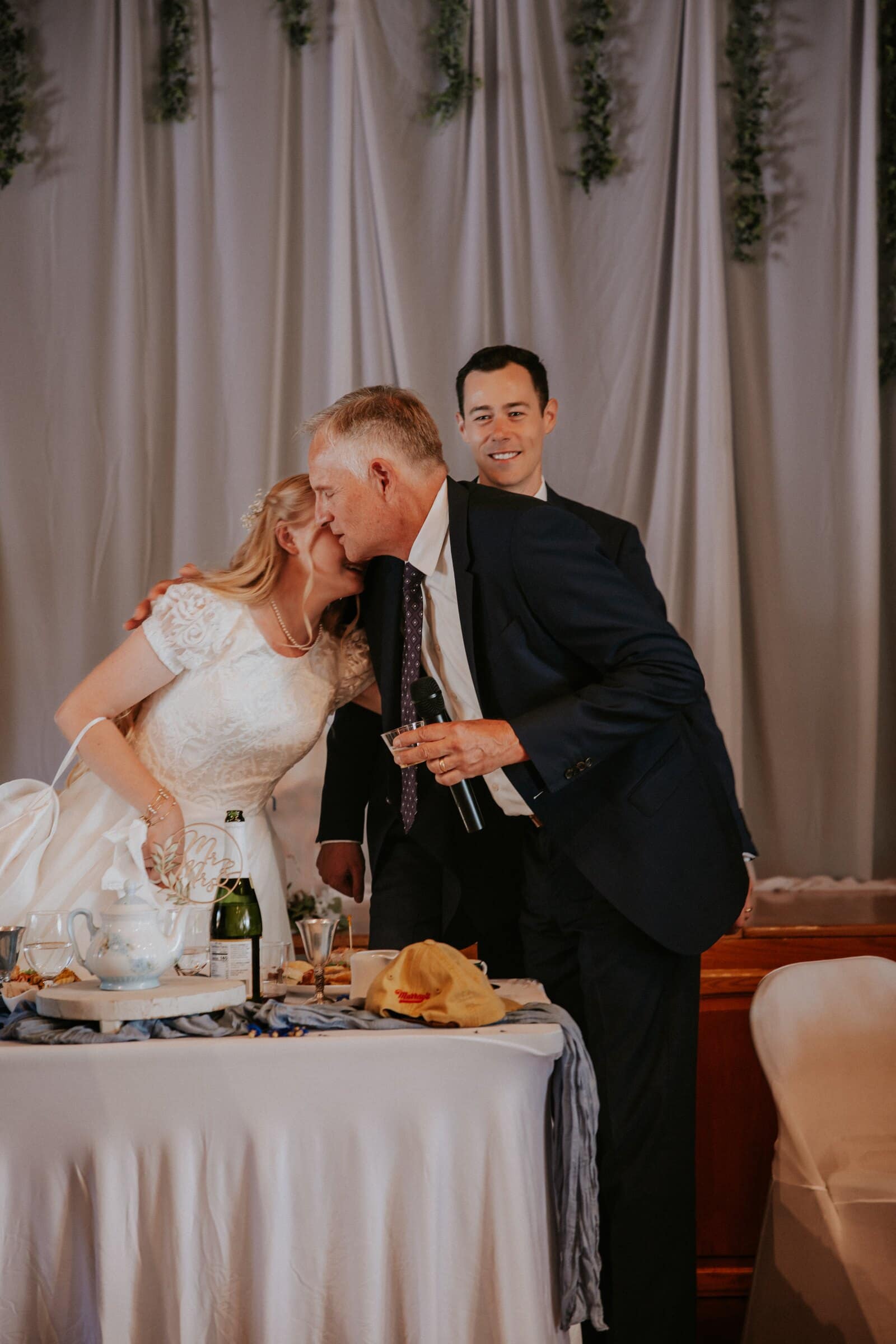 Morgan hugging a man in a dark suit at the head table
