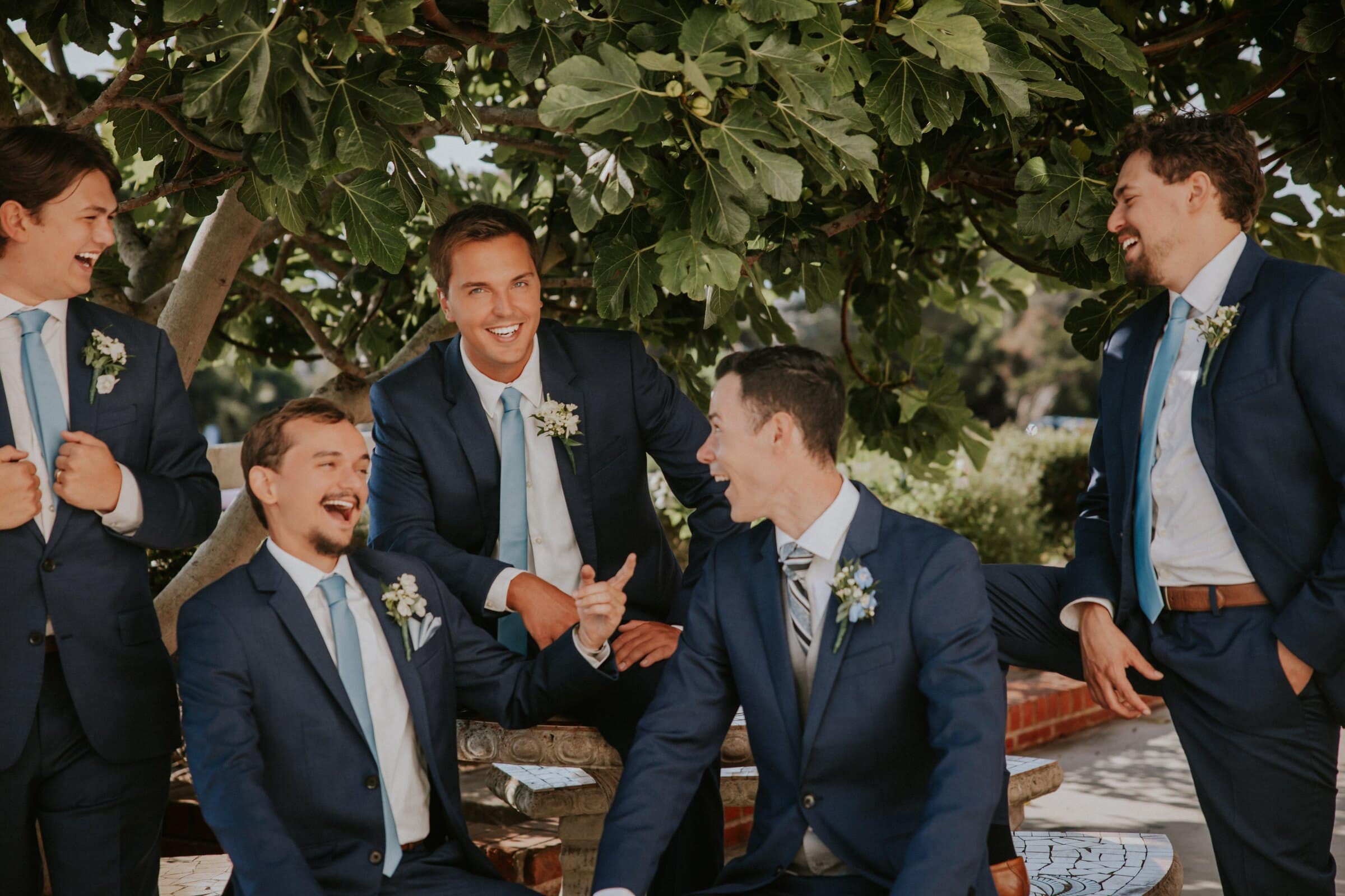 The groomsmen laughing together under a fig tree