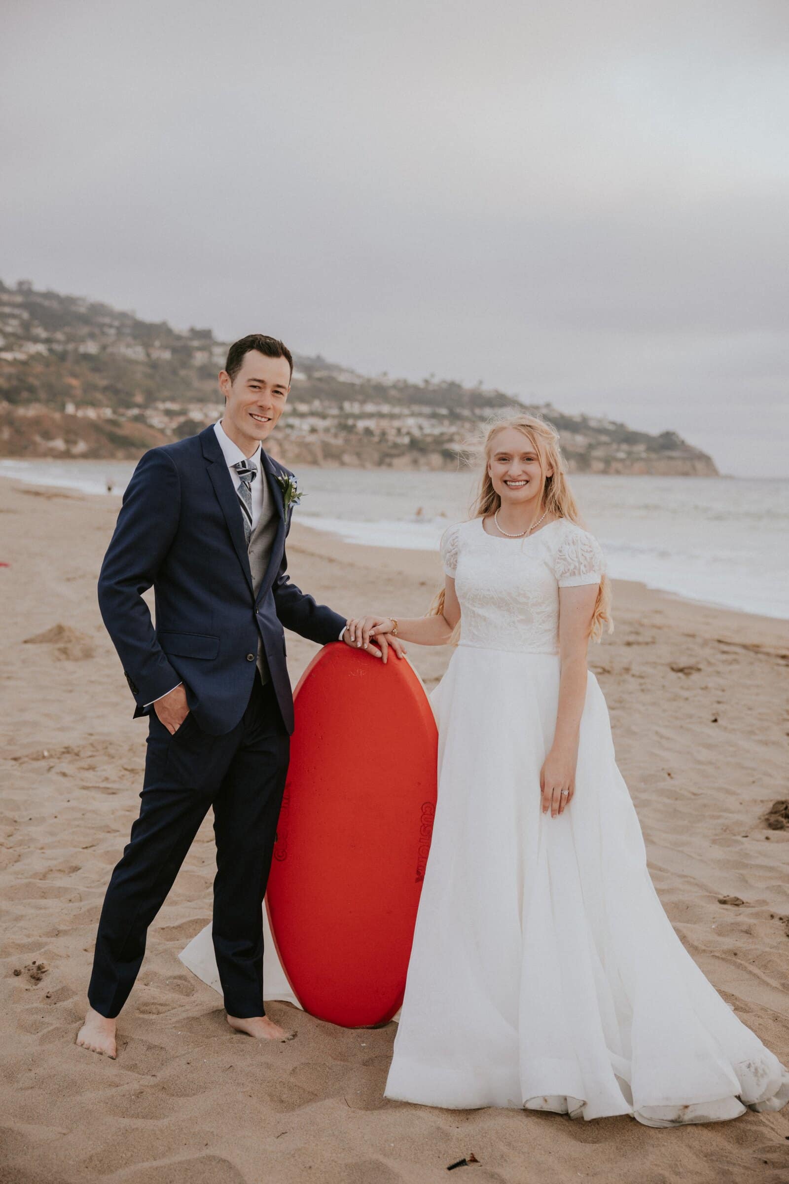 Bryce and Morgan on the sand beside a red bodyboard