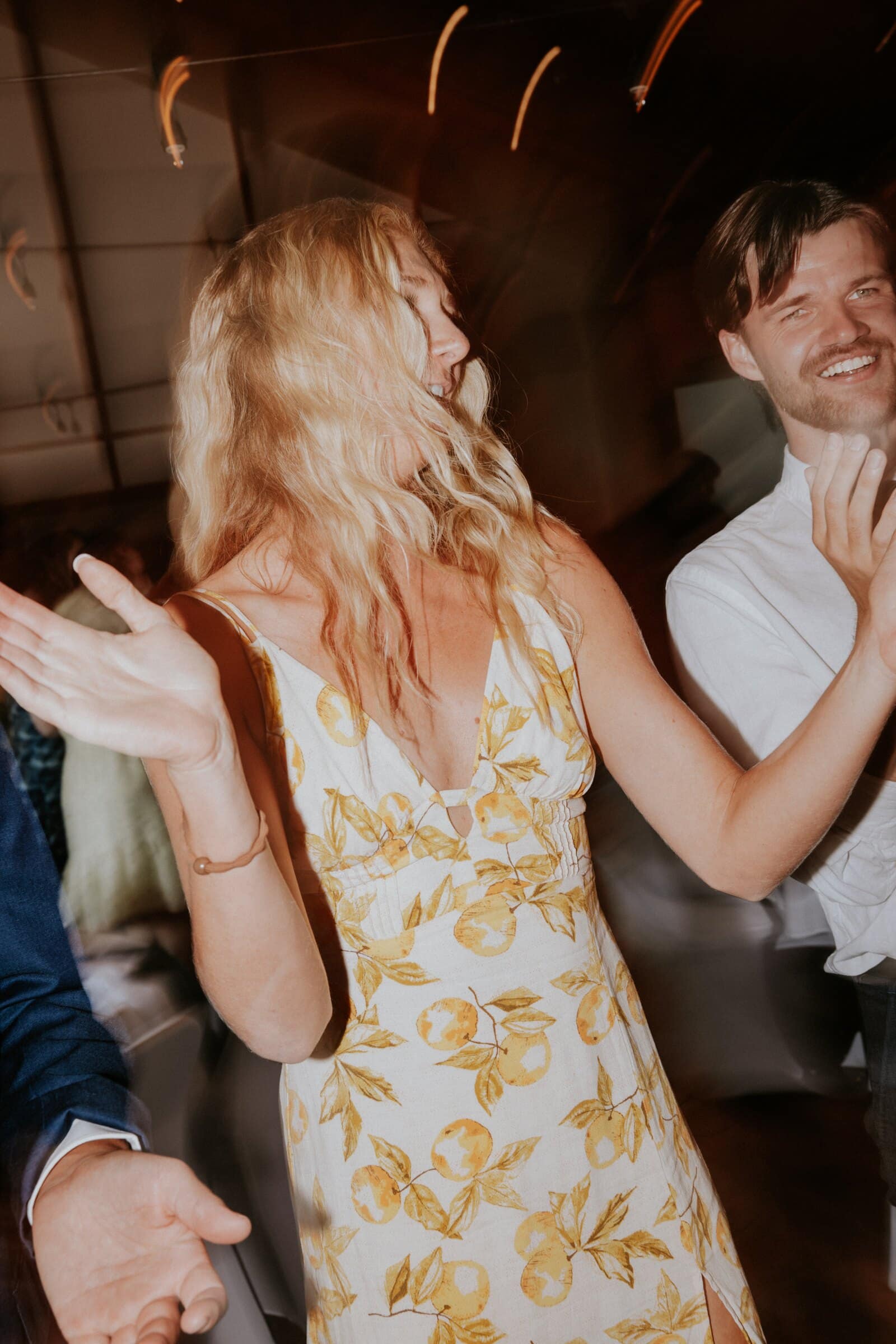 A guest in a yellow floral dress dancing as the lights streak
