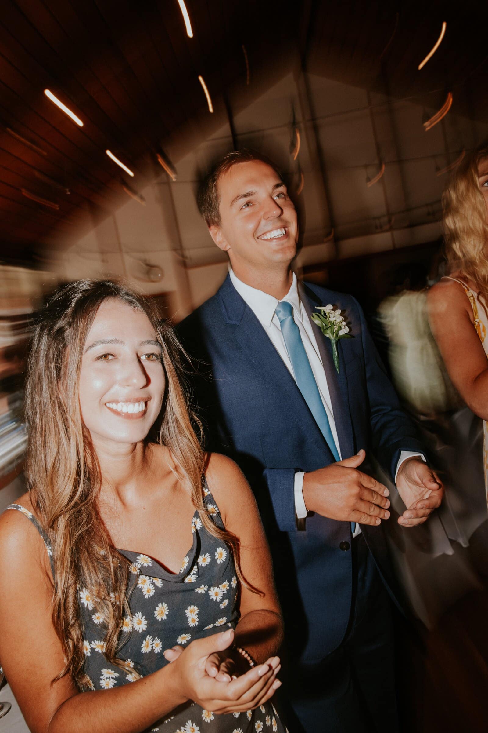 Two guests laughing on the dance floor, lights streaking behind them