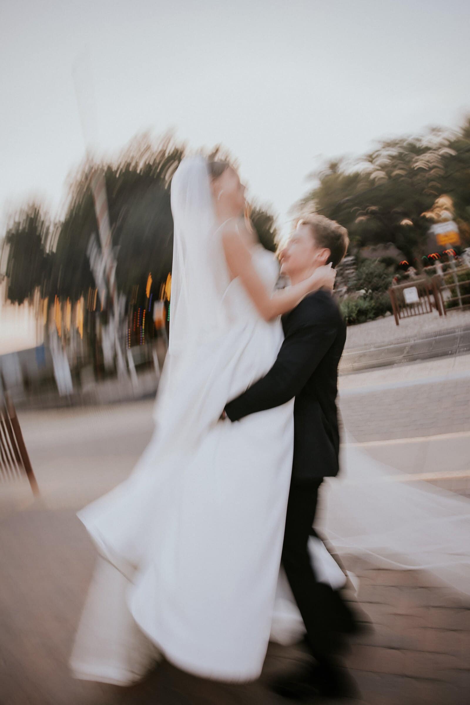 Grant spinning Clara in the street at dusk, the trees blurring behind them