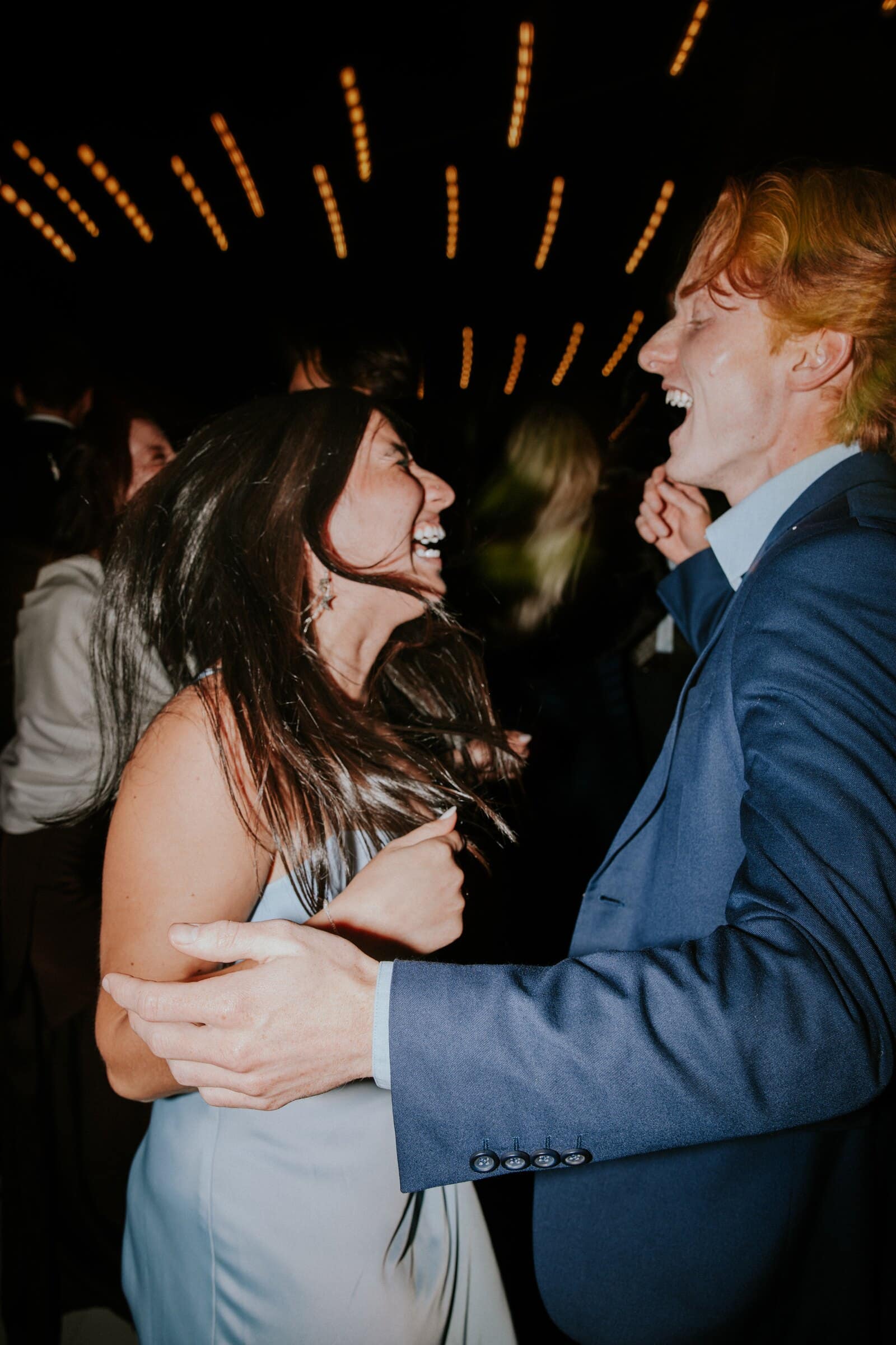 A couple laughing as they dance under streaks of light