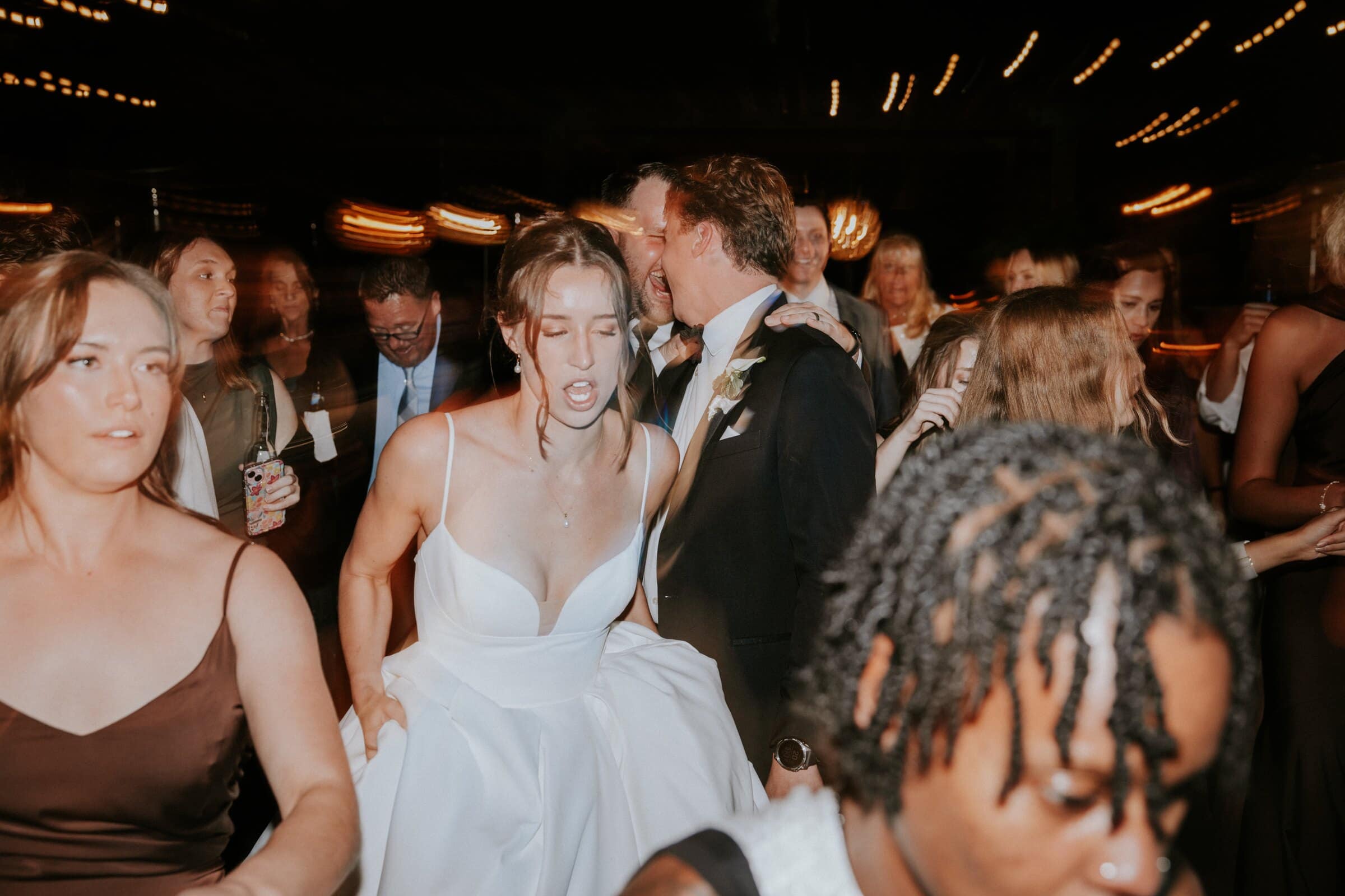 Clara and Grant in the middle of the dance floor with their friends, lights streaking overhead