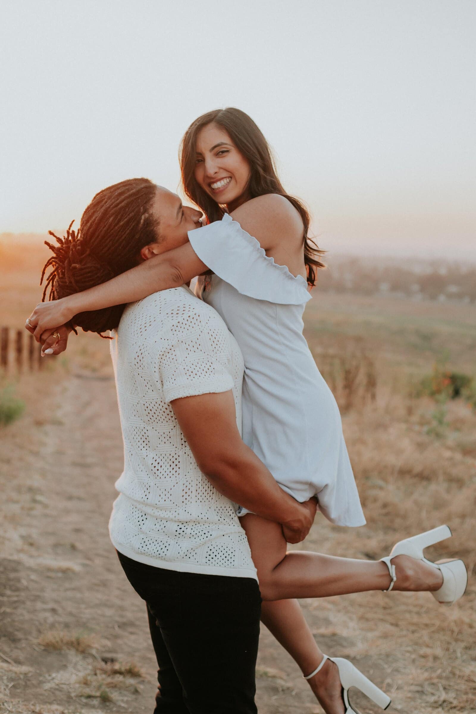 Jeremy lifting Ambica off her feet as she laughs at sunset