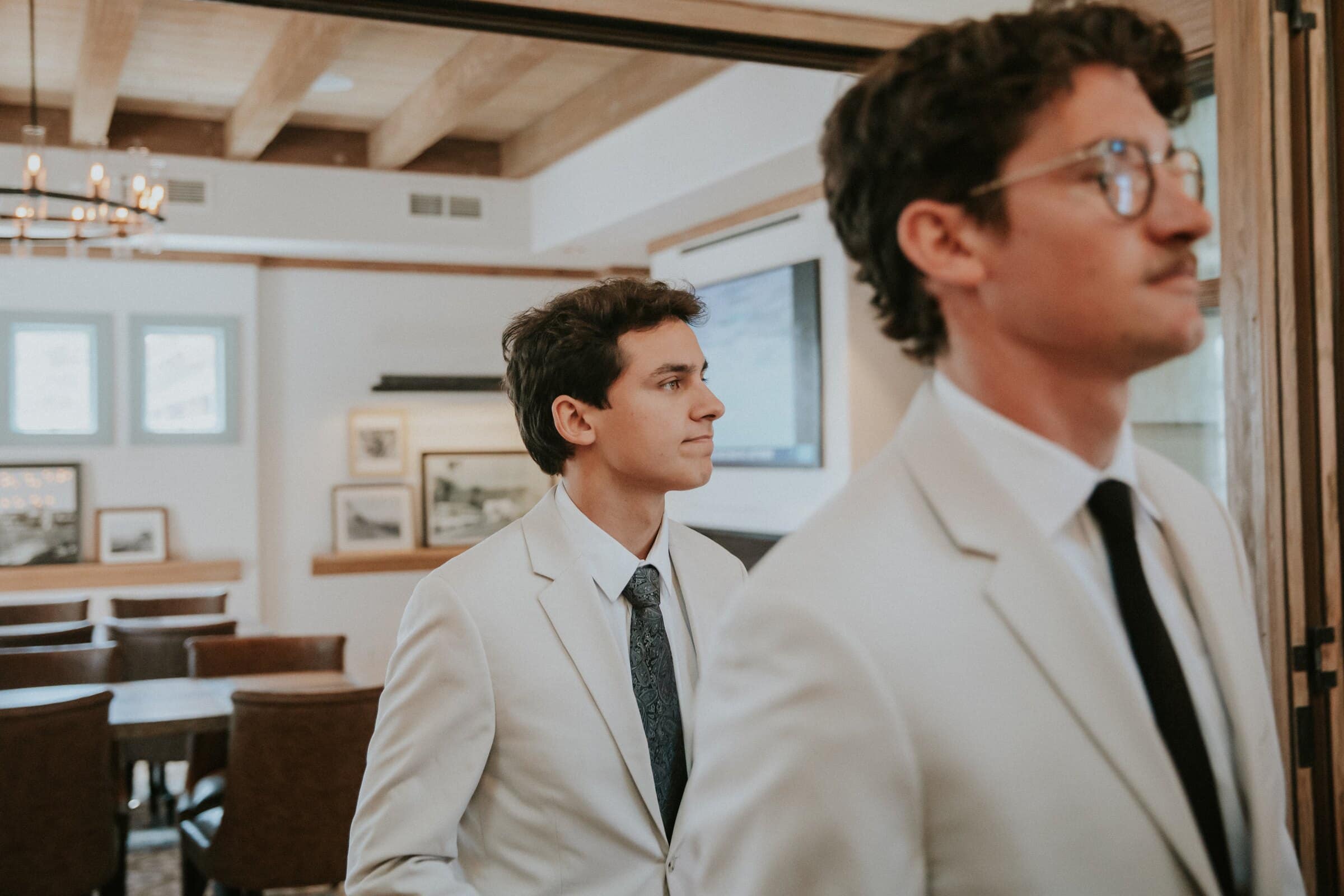 Two men in cream suits and dark ties waiting by the door