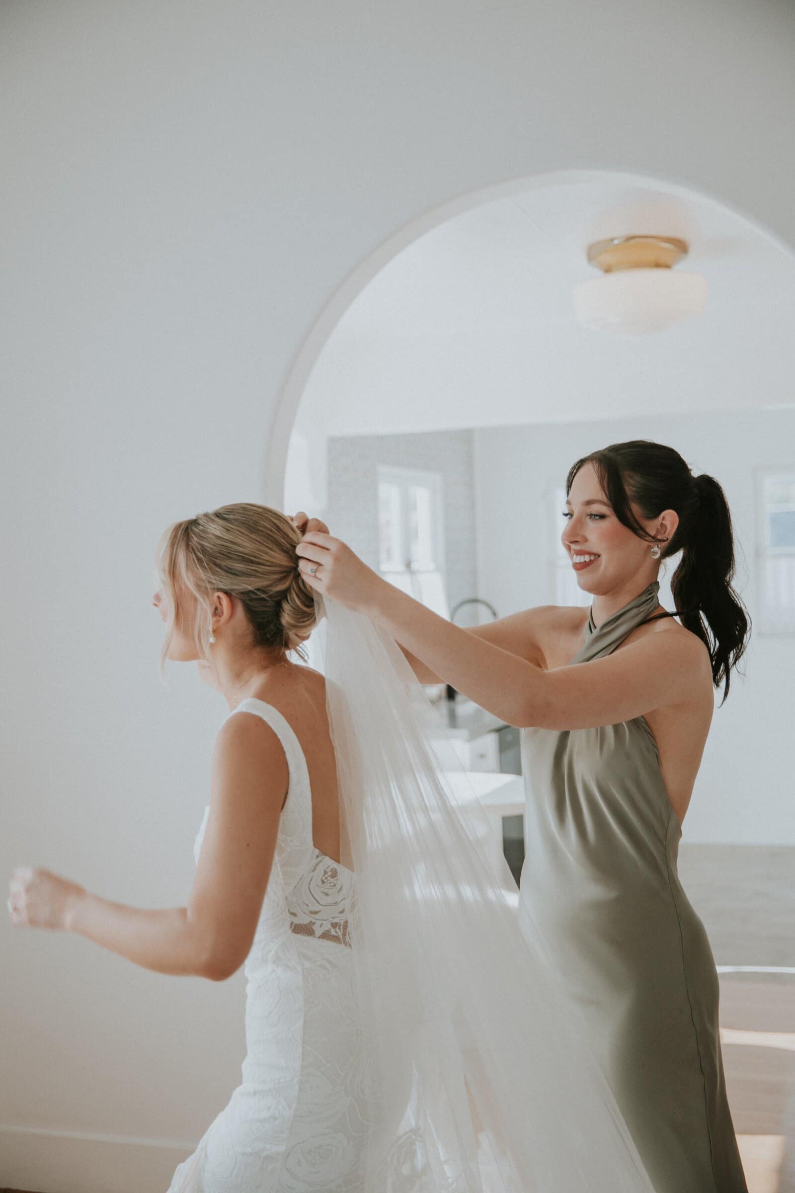 A bridesmaid in sage green setting Leilani's veil