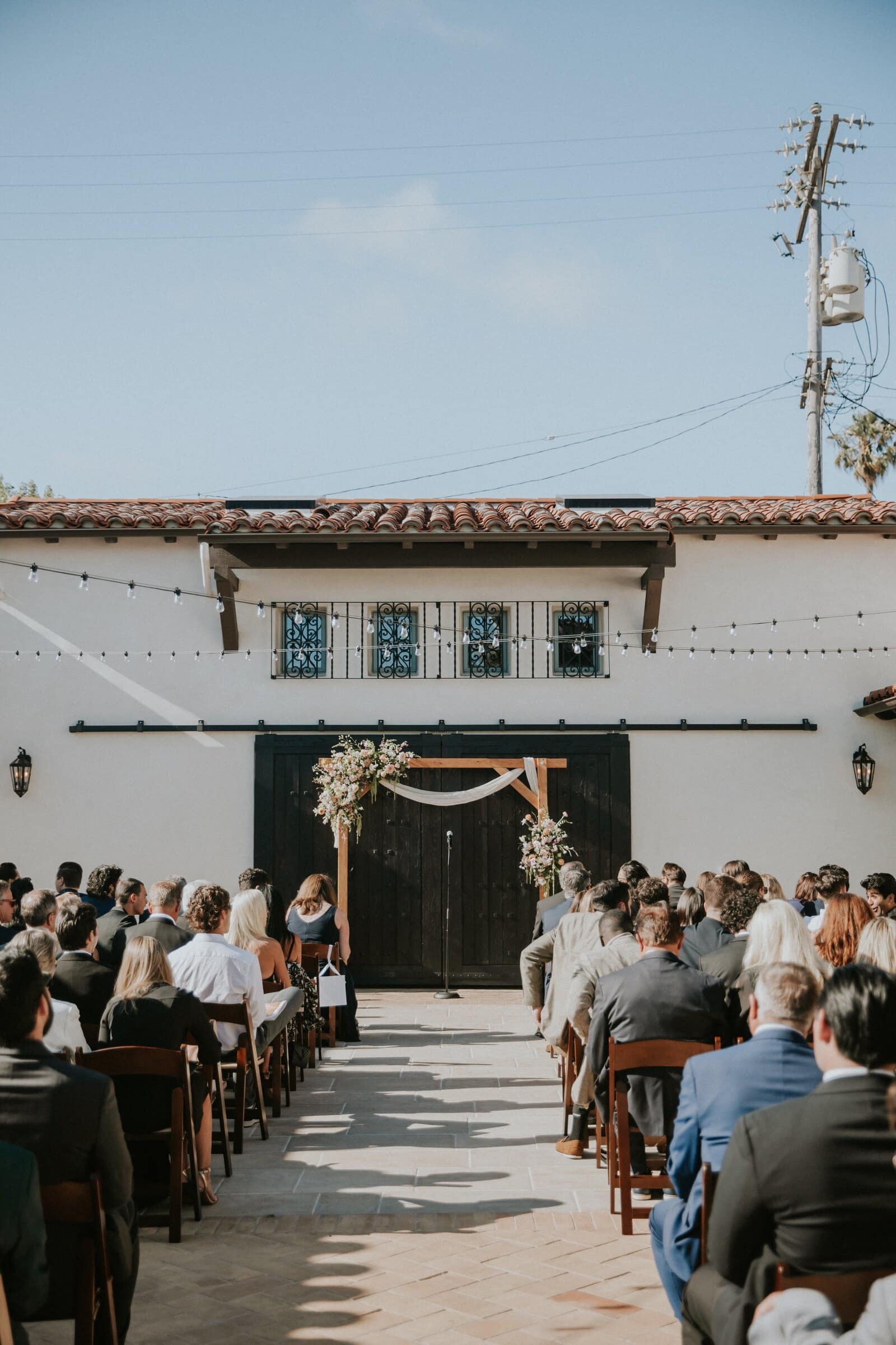 Guests seated in the courtyard facing the floral arch