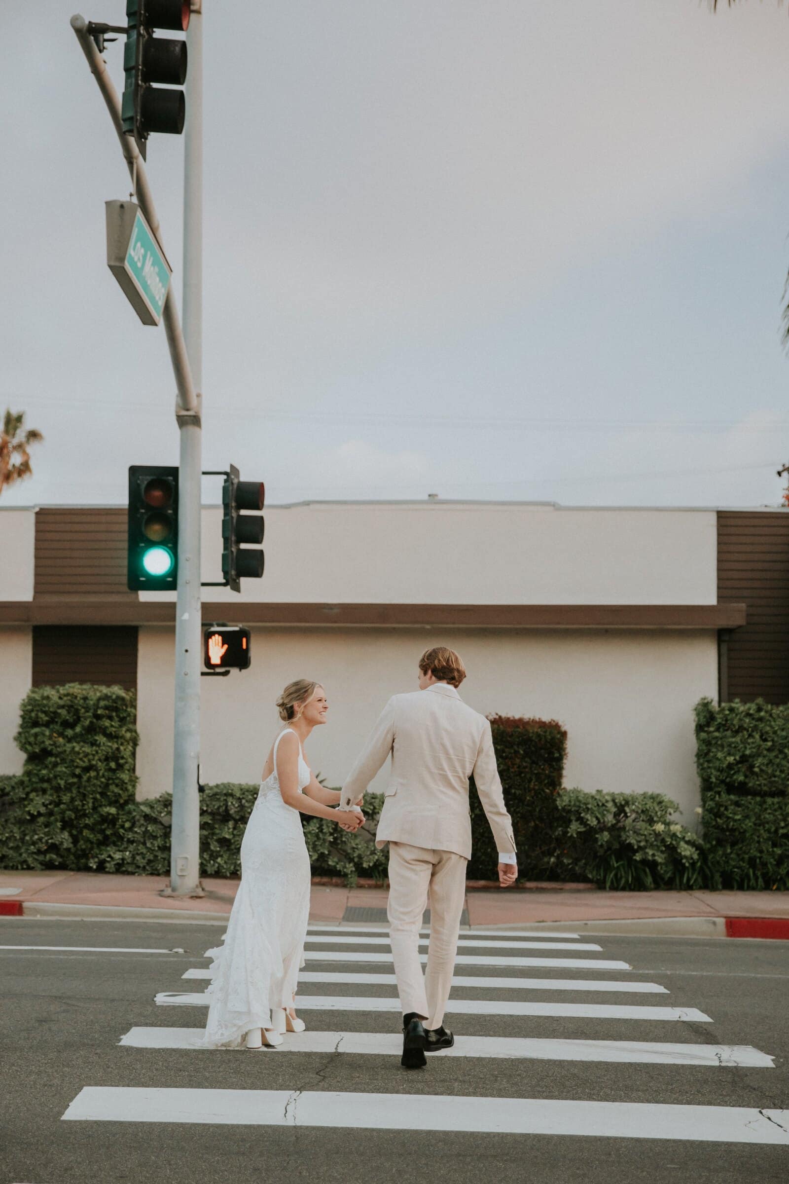 Micah and Leilani crossing the street hand in hand, seen from behind