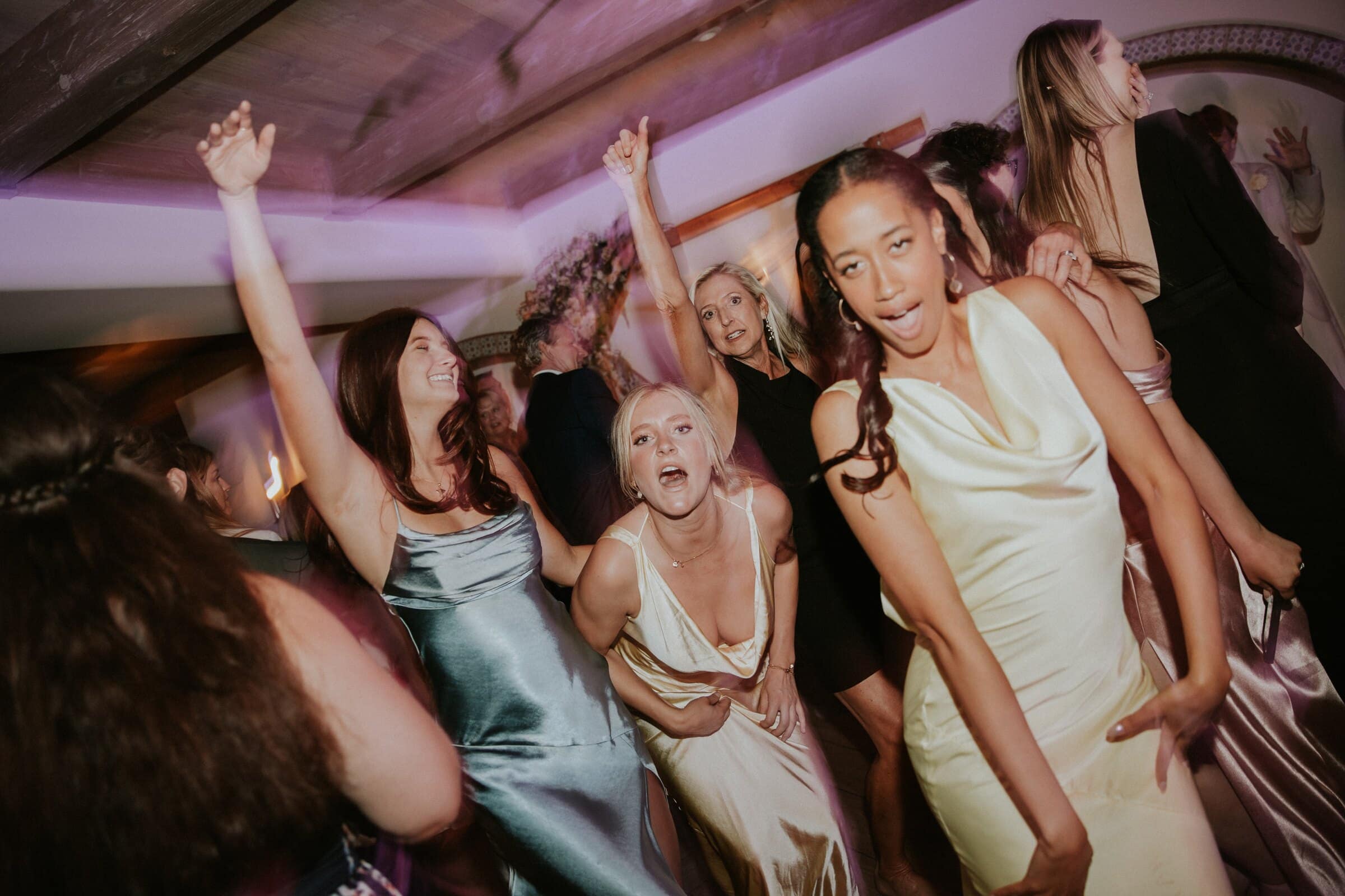 Bridesmaids in satin dancing with their arms in the air
